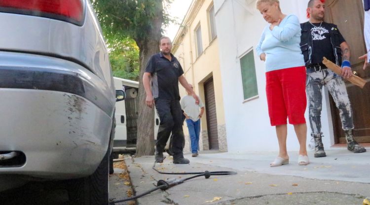 Pla detall d'una roda rebentada a Medinyà amb mecànic i veïns afectats al fons. ACN