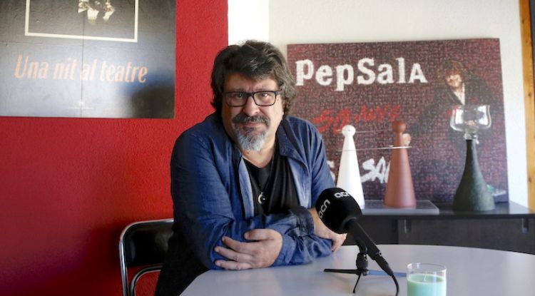 Pep Sala durant l'entrevista amb un cartell al seu darrere de la gira 'Una nit al teatre' de Sau. ACN