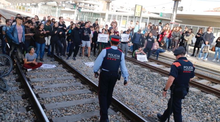 Dos agents dels Mossos i els assistents a la protesta que talla des de les tres de la tarda els trens. ACN