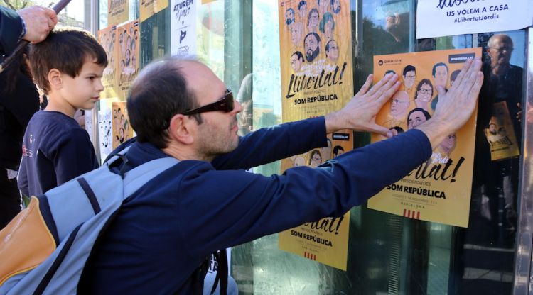 Un home enganxa un cartell per l'alliberament dels presos a la plaça Universitat de Barcelona. ACN