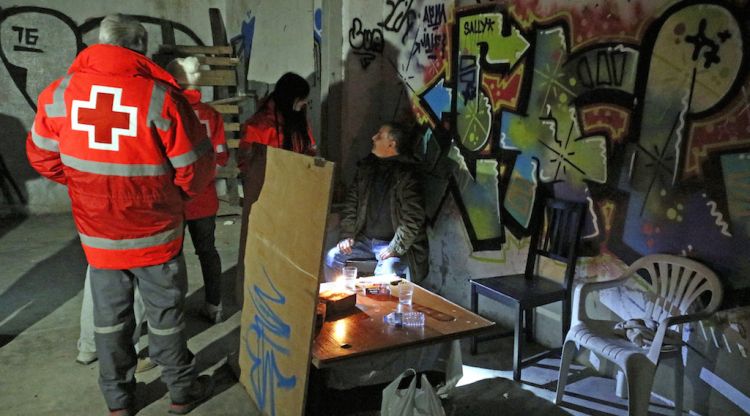 Voluntaris de la Creu Roja de Girona amb una persona que viu a les naus abandonades de la carretera Barcelona. ACN