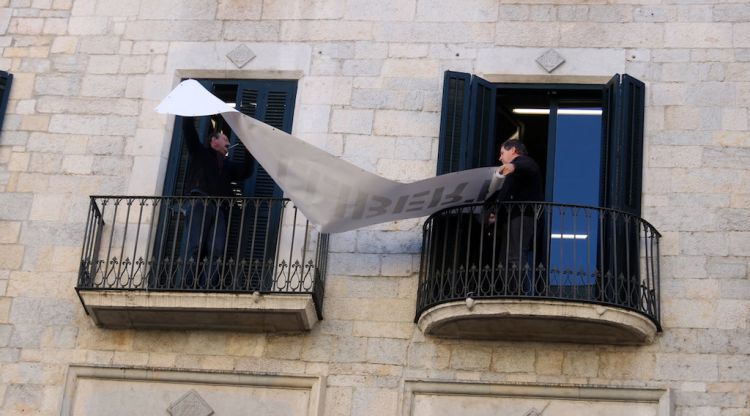 Moment en què s'ha retirat la pancarta dels presos de la façana de l'Ajuntament de Girona. ACN