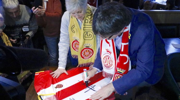 Puigdemont signant la samarreta del Girona que s'ha sortejat en la mitja part del partit contra el Getafe. ACN