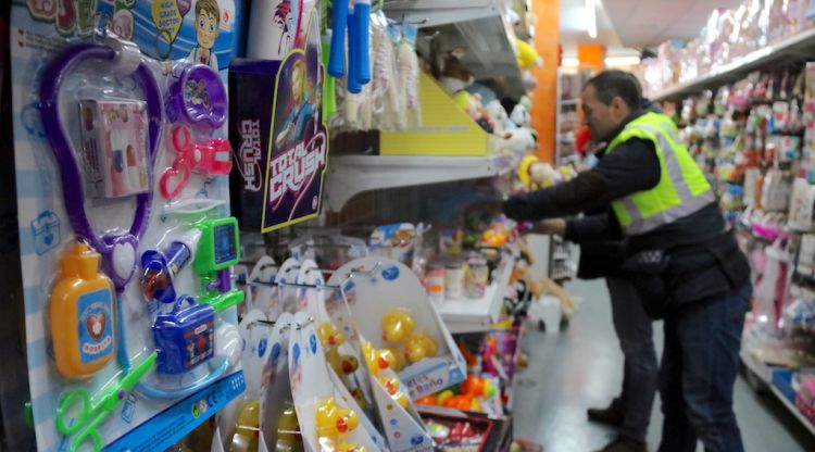 Dos agents de la Policia Municipal de Girona inspeccionant joguines d'un basar. ACN