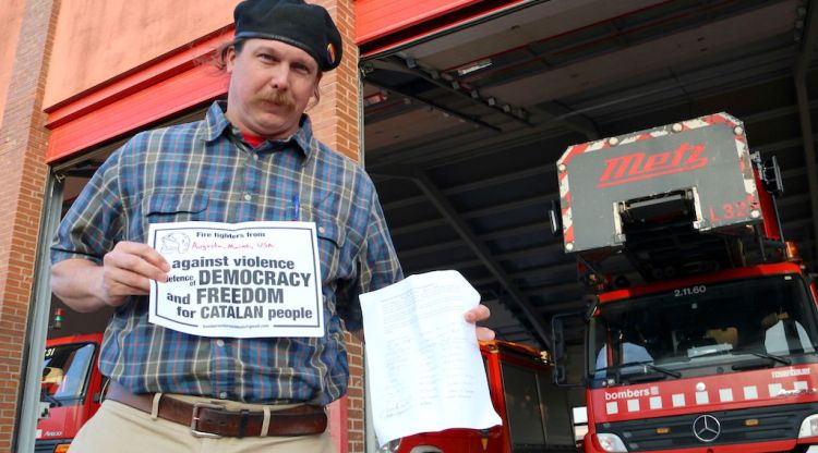 El bomber Ben Pratt mostrant les signatures que ha recollit als EUA per denunciar la violència de l'1-O. ACN