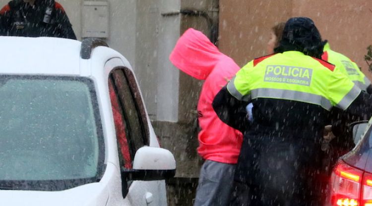 El fill del detingut, amb caputxa, arriba a la casa custodiat pels Mossos. ACN