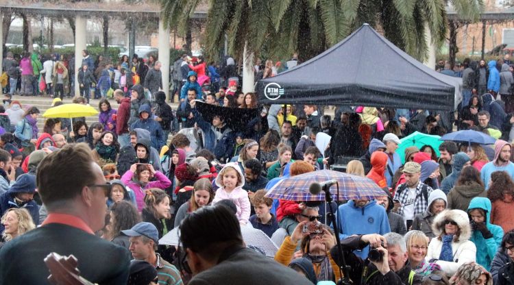 El públic assistent tapant-se de la pluja i els músics tocant. ACN