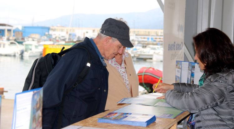Una parella de turistes parlant amb la informadora del Port de Roses. ACN