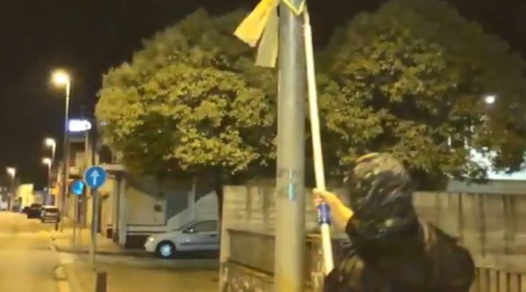 Una imatge extreta d'un dels vídeos de LiberaGerona on es veu un encaputxat a punt de retirar un llaç groc