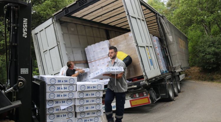 Uns homes retirant la càrrega manualment del camió bolcat a Riudarenes. ACN