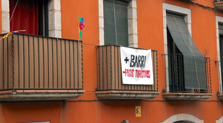Una façana al Barri Vell de Girona on es veu una pancarta en contra dels pisos turístics. ACN