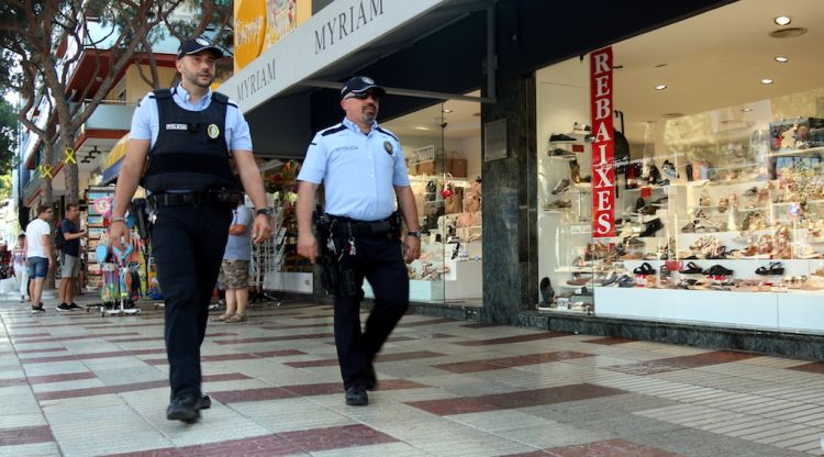 Dos agents de la Policia Local de Platja d'Aro, d'esquenes, patrullant pel centre del municipi. ACN