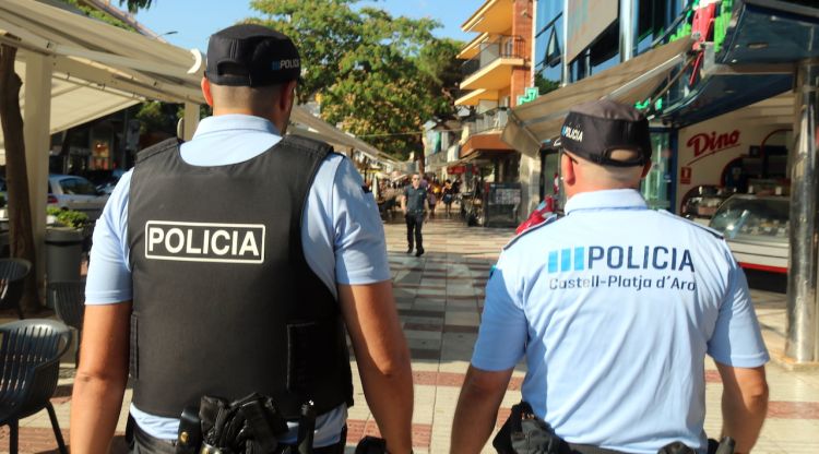 Dos agents de la Policia Local de Platja d'Aro, d'esquenes, passejant pel centre del municipi. ACN
