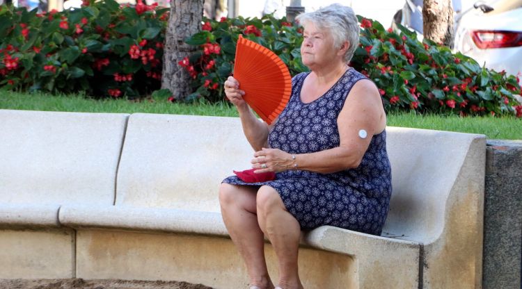 Una dona fent-se vent amb un ventall en una plaça pública de Figueres davant l'onada de calor. ACN