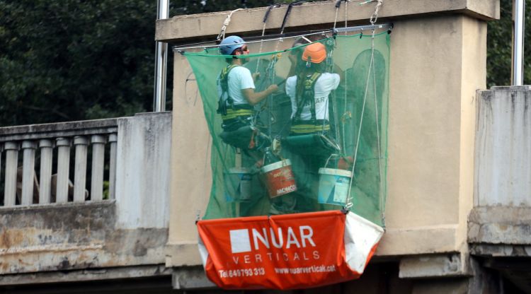 Els operaris traient un dels escuts amb les àligues franquistes del pont de l'Aigua. ACN