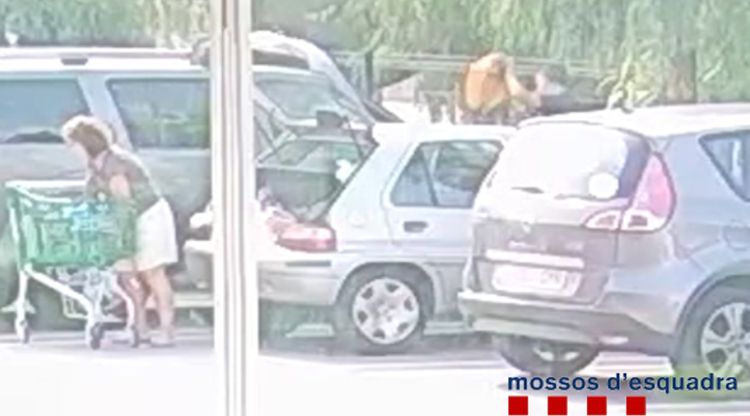 Pla obert d'un cotxe amb una de les víctimes posant la compra al maleter, en el moment en què els lladres li sostreien la bossa de mà