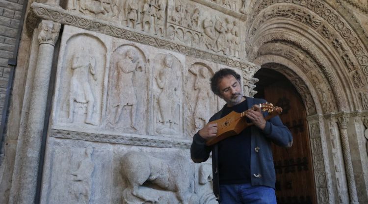 El musicòleg Antoni Madueño tocant un instrument medieval davant la Portalada de Ripoll. ACN