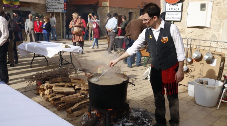 Pla obert d'un home barrejant l'olla de ranxo durant la VII Trobada d'Escudellers, Ranxos, Sopes Històriques a Capmany. ACN