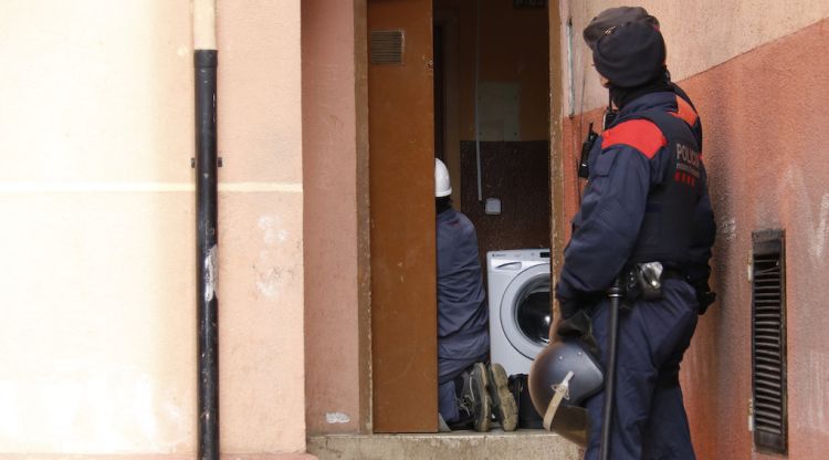 Dos agents protegint a dos dels tècnics d'Endesa que estan revisant els comptadors punxats a Font de la Pólvora. ACN