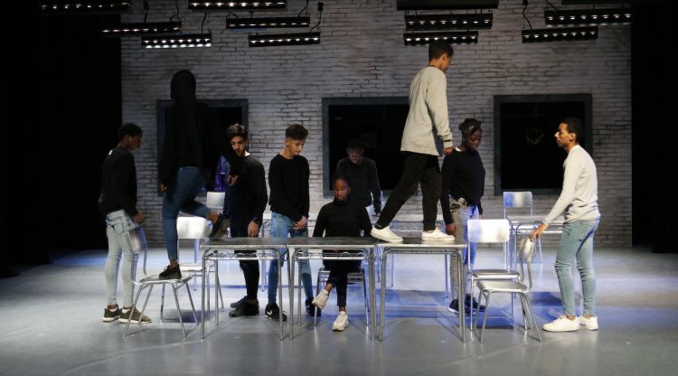 Els alumnes enfilats a sobre les taules, interpretant una de les escenes de l'obra 'El cos es cola'. ACN