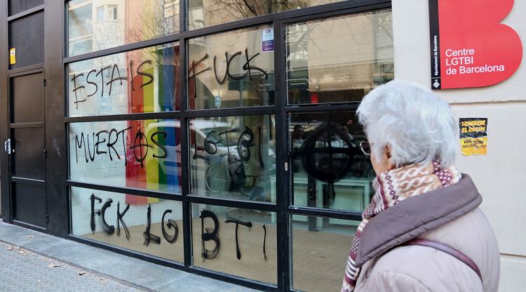 El centre LGTBI de l'Ajuntament de Barcelona, ple de pintades feixistes, mentre una veïna ho observa. ACN