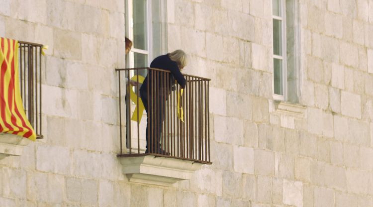 Dues treballadores retirant els llaços grocs del balcó de la delegació de la Generalitat a Girona. ACN