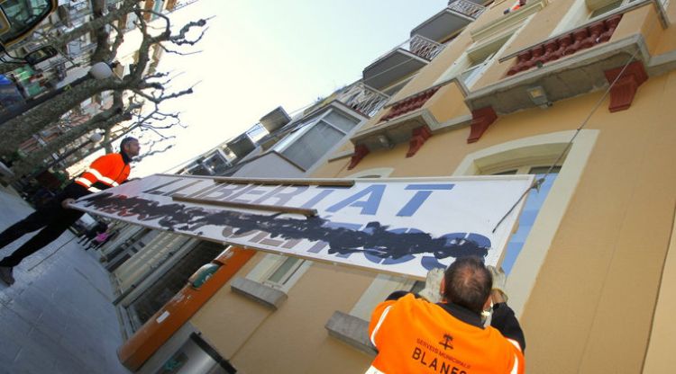 Operaris municipals despenjant la pancarta de Blanes