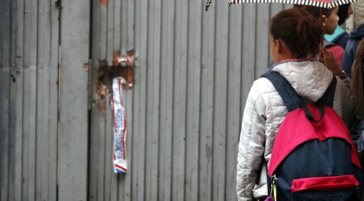 Una alumna es mira els desperfectes de la porta del col·legi Verd de Girona. ACN