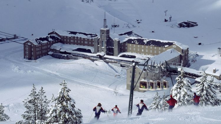 Uns esquiadors baixen per una de les pistes de la Vall de Núria, amb el complex al fons