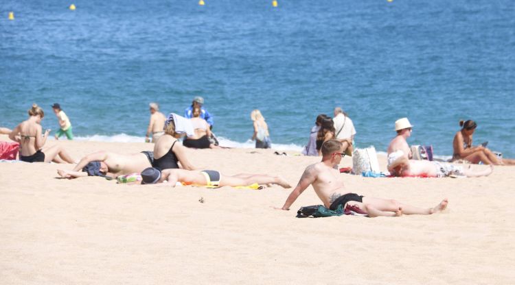 Diversos turistes estirats a la platja prenent el sol a Lloret. ACN