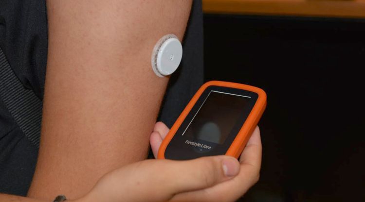 Un usuari mesurant el nivell de glucosa a partir del sistema flaix en què aproxima un dispositiu a un sensor. ACN
