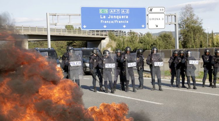 La Policia Nacional i una barricada cremant a l'AP-7 a Girona Oest el dimarts. ACN