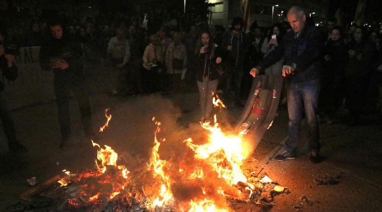 Un manifestant cremant una foto de Felip VI cap per avall durant la protesta. ACN