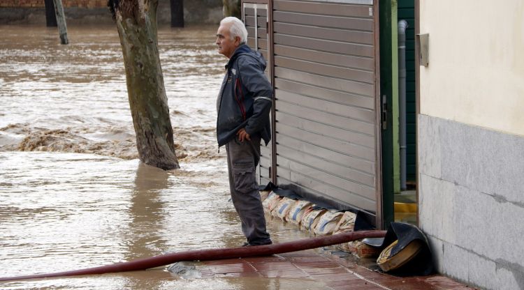Un senyor a la porta el jardí de la residència d'avis d'Agramunt bombant aigua per la rovinada del Sió. ACN