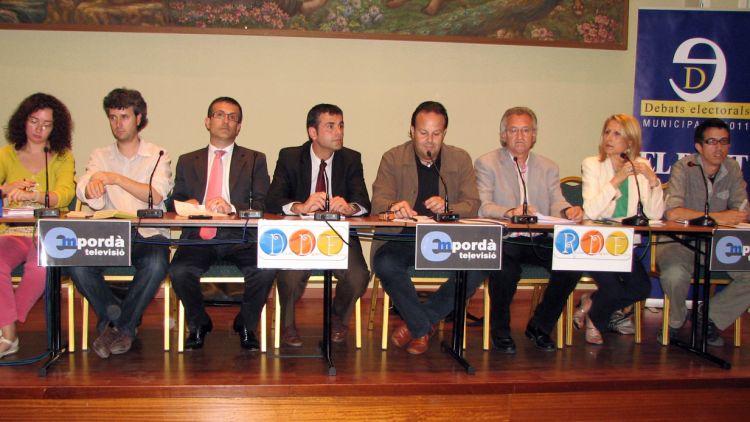 Els set candidats que opten a l'alcaldia de Figueres amb el moderador al centre © ACN