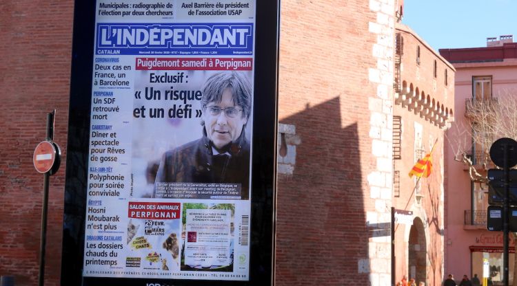 En primer terme, un cartell amb la portada de L'indepéndant on hi apareix Carles Puigdemont; al fons, el Castellet de Perpinyà. ACN
