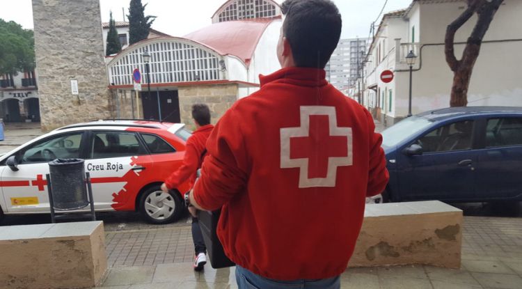 Membres de la Creu Roja carregant el vehicle de menjar per a repartir-lo