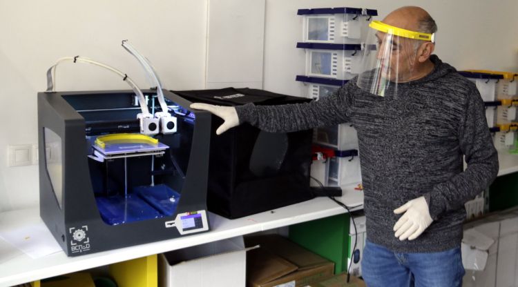El responsable d'Innova Didàctic d'Olot amb una de les impressores 3D que fan pantalles facials. ACN