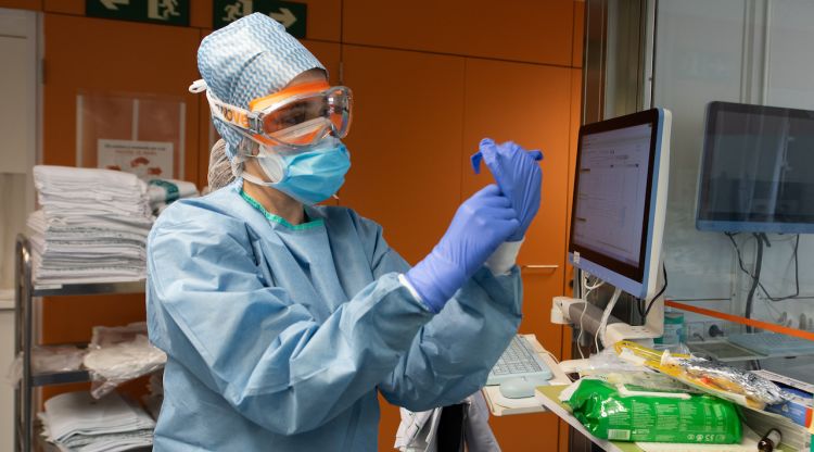 Una professional sanitària es posa guants abans d'entrar en una habitació ocupada per un pacient amb coronavirus a l'Hospital Clínic. ACN