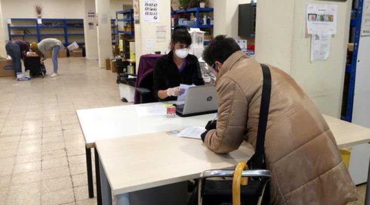 Una usuària del centre de distribució d'aliments de Girona recollint els seus lots. ACN