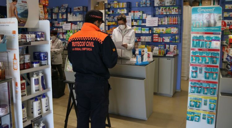Un voluntari de Protecció Civil en una farmàcia de la Bisbal d'Empordà anant a buscar un medicament per a una persona gran. ACN