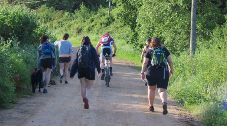 Diverses joves caminant mentre un ciclista passa pel mig entrant a les Gavarres a la Bisbal d'Empordà. ACN