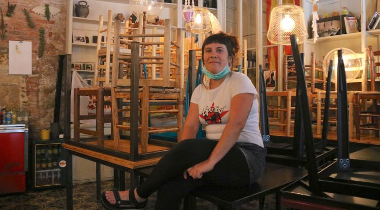Maria Roura, responsable del bar Ca la Pila Dumingu, de la Bisbal d'Empordà, amb les cadires de la terrassa a dins del bar. ACN