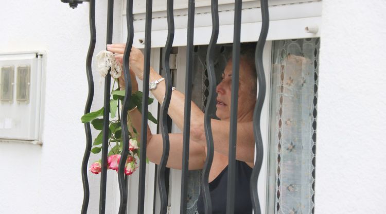 Una dona penjant una flor a la finestra de casa seva al barri de Sant Narcís de Girona aquest matí. ACN