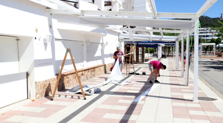 Diversos operaris arreglant el tendal d'una terrassa en un bar de Tossa de Mar. ACN