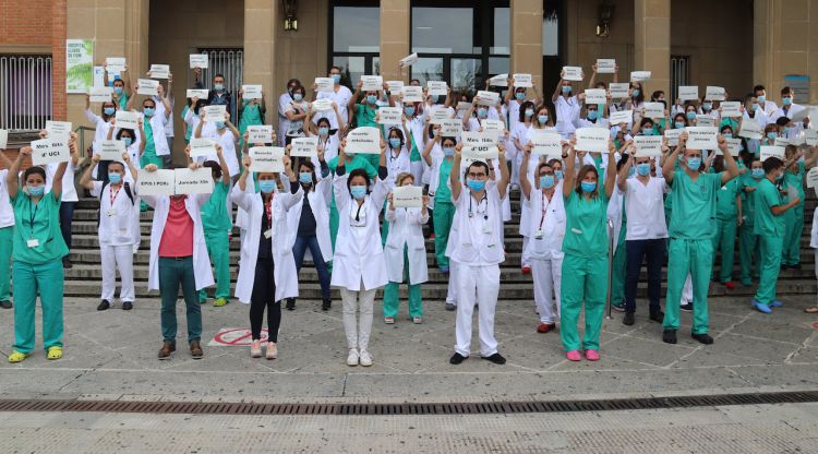 Els treballadors del Trueta demanant més hores de descans pel personal sanitari aixecant papers reivindicatius a les escales de l'hospital. ACN