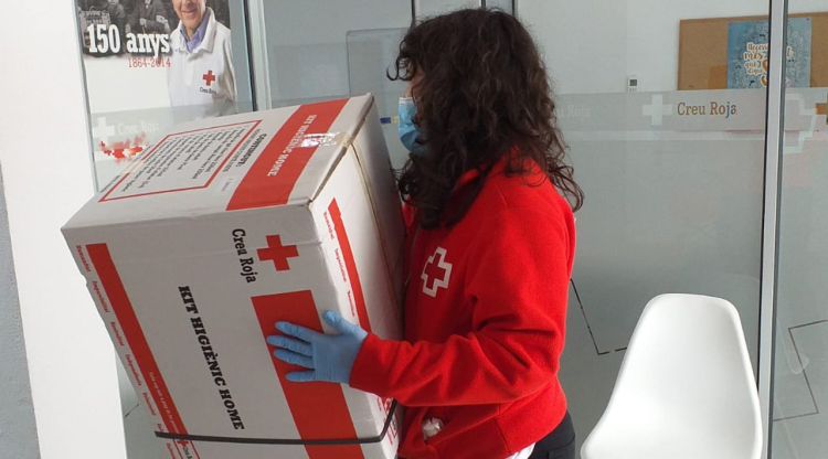 Una voluntària de la Creu Roja entregant un kit d'ajuda