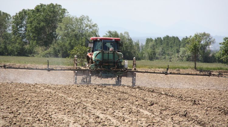 Un tractor tirant herbicida en un camp © ACN