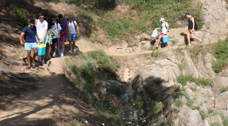 Uns joves caminant pel camí de ronda de Tamariu amb un arrant d'un penya segat. ACN