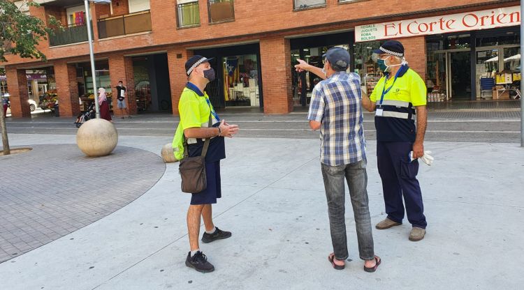 Dos agents cívics informant a un ciutadà de Salt com ha de dur la mascareta